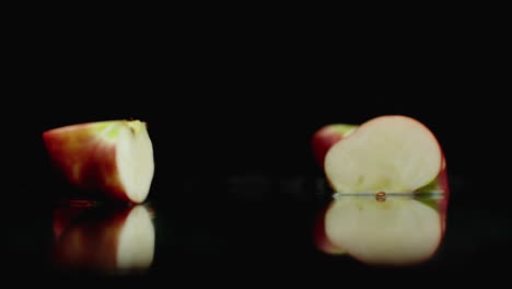 Red-juicy-sliced-​​apple-falling-on-a-glass-with-splashes-of-water-in-slow-motion-on-a-dark-background